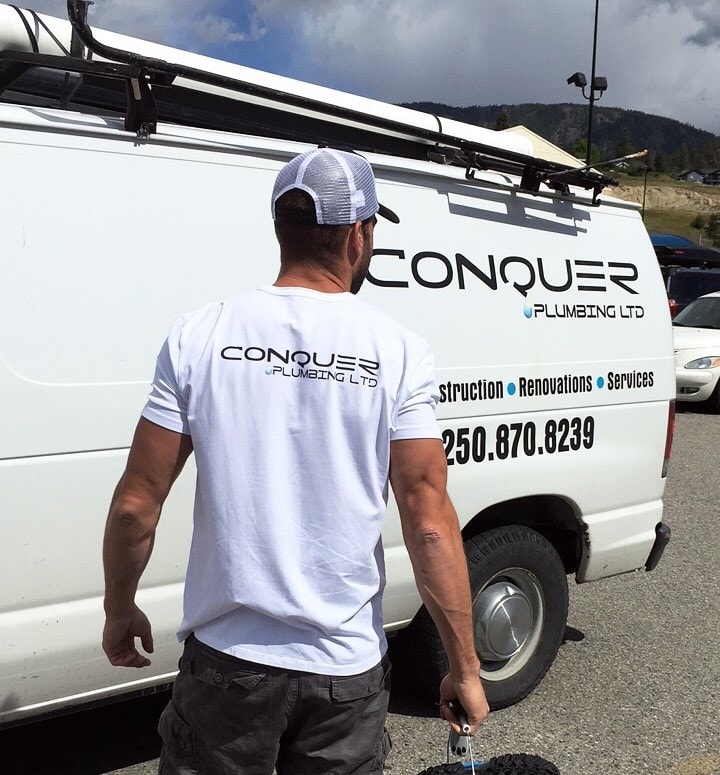 Conquer Plumbing tradesperson beside service van